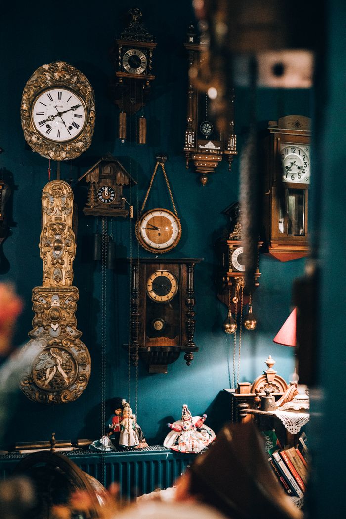 A collection of vintage wall clocks displayed in a cozy, warmly lit room.